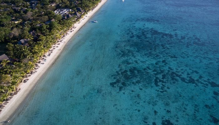 A panoramic view of Trou Aux Biches beach in Mauritius, showcasing turquoise waters, palm trees, and white sandy shores