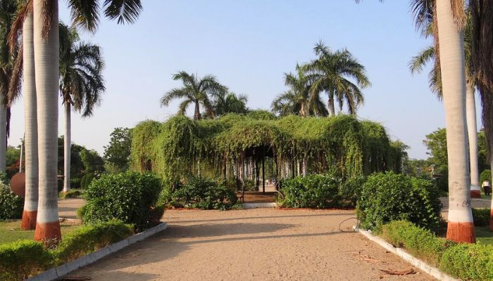 A picturesque scene of Ajwa Nimeta Garden with beautifully landscaped lawns, colorful flowerbeds, and a serene lake