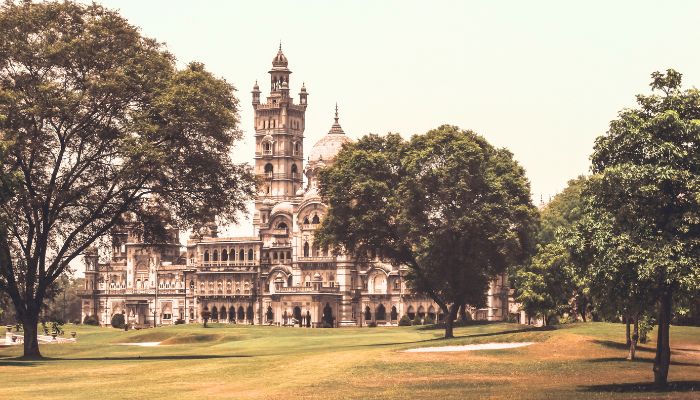 A grand view of Laxmi Vilas Palace in Vadodara, showcasing its intricate Indo-Saracenic architecture with lush green lawns in the foreground