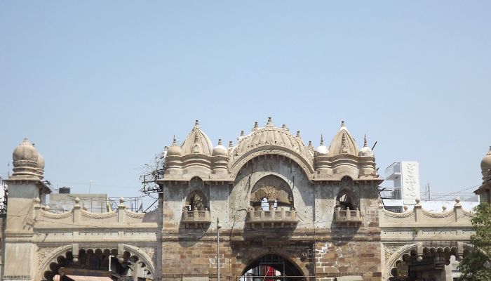 The historic Mandvi Gate in Vadodara, featuring its grand arches and intricate carvings, illuminated by soft evening lights