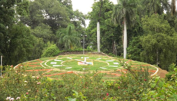 A scenic view of Sayaji Baug in Vadodara, featuring well-manicured gardens, tall trees, and vibrant flowers