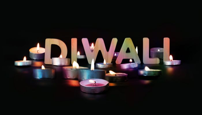 The word "Diwali" with lit tealight candles against a dark background