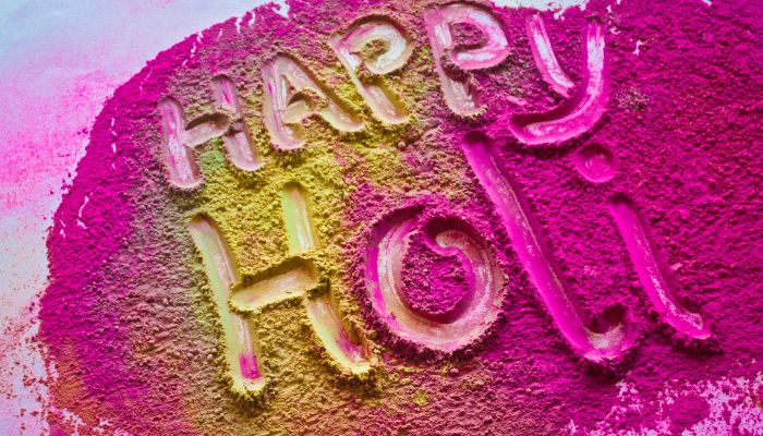 "Happy Holi" written in vibrant colored powders