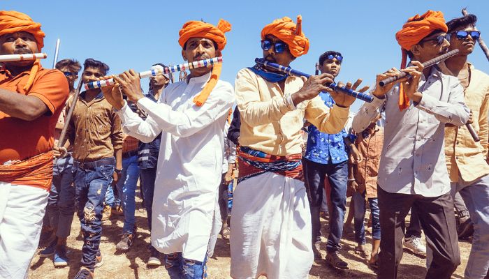 A lively scene from the Kavant Fair in Gujarat, featuring tribal dancers in traditional attire, colorful decorations, and a bustling crowd enjoying the festivities in a rural setting.