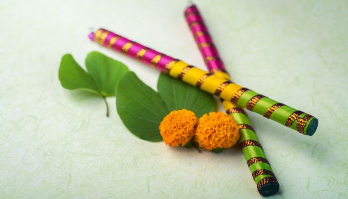 Colorful Dandiya sticks with green leaves and marigold flowers