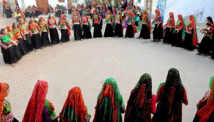 A bustling scene from the Ravechi Fair in Gujarat, with devotees in traditional attire, colorful stalls, and lively cultural performances near the Ravechi Mata Temple.