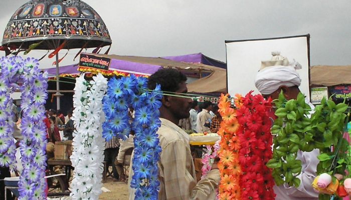 Visitors enjoy the vibrant Tarnetar Fair with decorated canopies, traditional dance performances, and various stalls in Gujarat, India