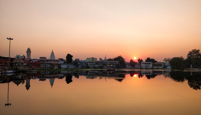 A peaceful lakeside view at Dakor Campsite with tents set up near the water and surrounded by lush greenery