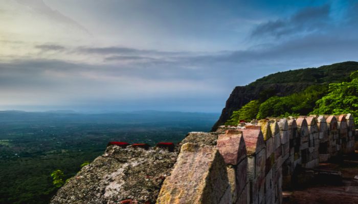 A panoramic view of Pavagadh Adventure Camp with rugged hills, dense greenery, and adventure activities set against the backdrop of a historic fort