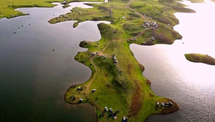 Aerial view of Vishal Khadi Eco Campsite featuring a lush green peninsula extending into a lake